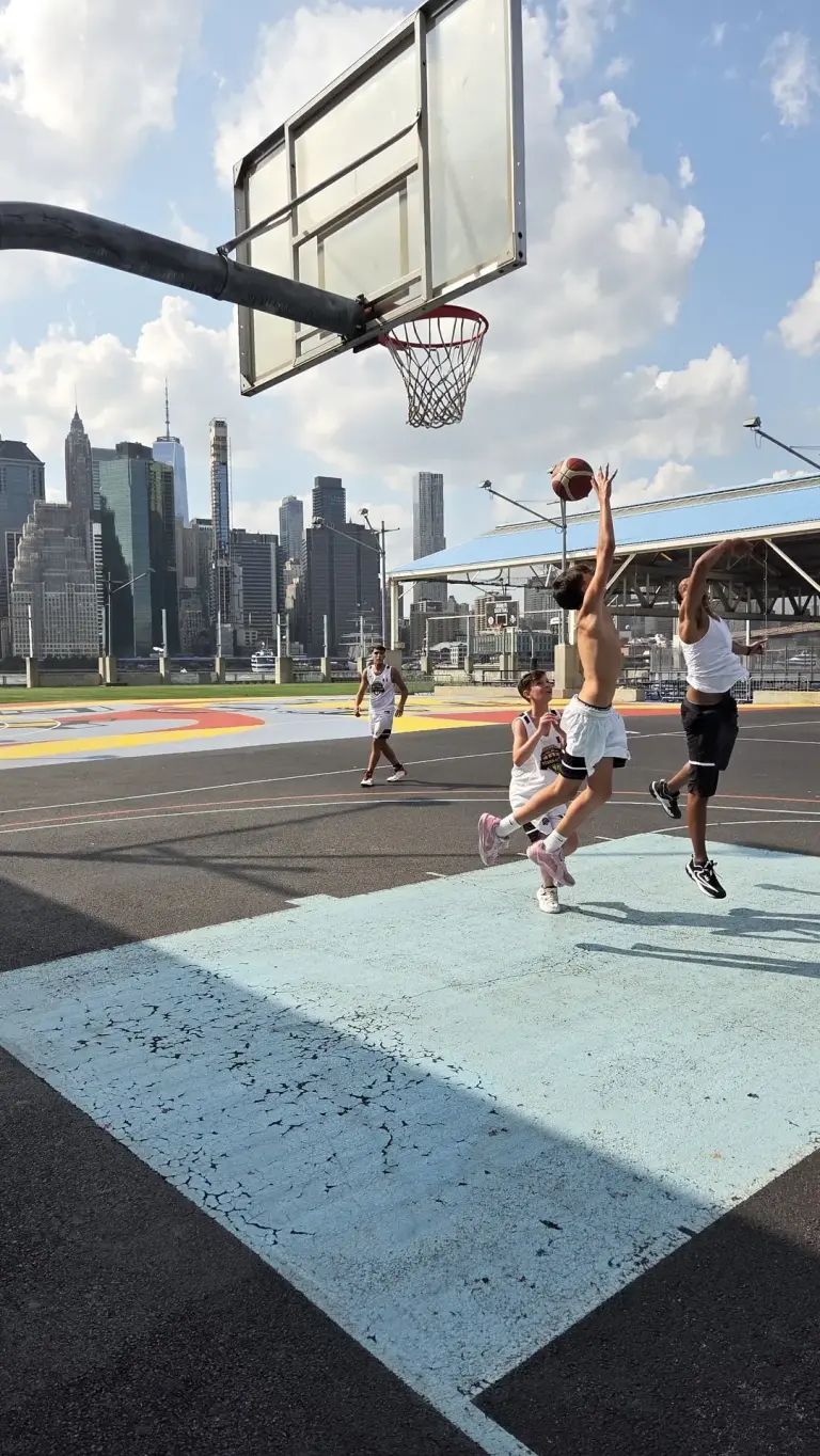 Un ragazzo salta a canestro al playground di Brooklyn